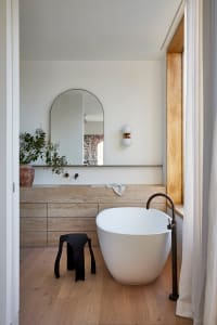 A modern bathroom featuring a freestanding tub, sink, and vanity with marble finishes and a minimalist design.