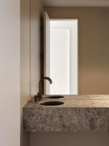 A minimalist bathroom featuring a modern marble countertop with two sinks and a sleek faucet.