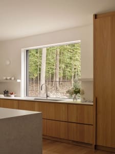 Modern residential kitchen featuring a concrete countertop and wooden cabinets.