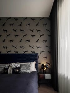 A modern minimalist bedroom with textured fabric bedding and leopard print wallpaper