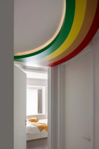 Minimalist bedroom featuring colorful decorative trims on the ceiling.