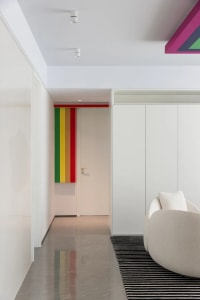 Minimalist living room with white furniture, multicolored rug, and modern decor