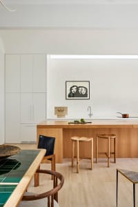 A modern kitchen featuring marble countertops and wooden stools.
