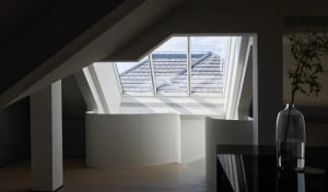 A modern bathroom featuring white stone tiles on the walls and floor, with a window providing natural light.