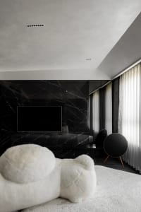 A modern bedroom with black marble walls, white furniture, and a large window.