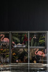 A modern decorative bar cabinet with glass-paneled doors, showcasing a variety of glassware and decor items.
