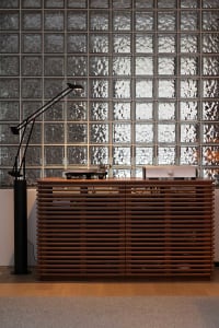 A modern industrial interior design featuring glass block walls and wooden furniture.