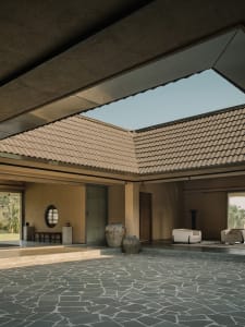 A modern living room with concrete walls, a stone floor, and a skylight.