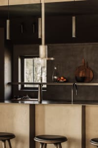 Minimalist kitchen with metallic countertops and stools, featuring sleek, modern design elements.