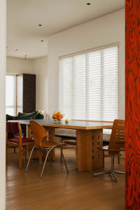 Modern dining room featuring a wooden table with chairs and a bowl of fruit on the table.