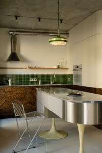 A modern kitchen featuring concrete tiles, a bar stool with a unique metal frame, and a minimalist design.