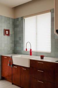 Modern kitchen featuring tile backsplash, concrete countertops, and wooden cabinets in front of a large window.