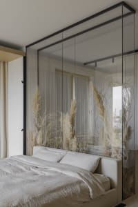Bedroom featuring a bed with white bedding and pampas grass, behind a glass partition.