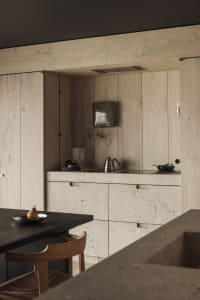 Minimalist kitchen with stone countertop and cabinets, featuring modern design elements.