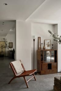 A modern living room featuring a wood armchair with a concrete floor, providing a comfortable and stylish lounge area.
