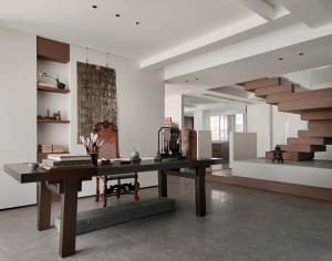 A modernist living room with a concrete staircase and minimalist decor.