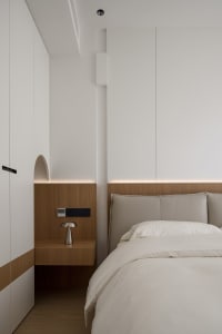 A modern bedroom with white paneling on the walls and a wooden headboard and nightstand.