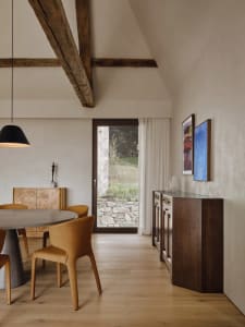 Modern dining room with a wooden table, glass chairs, and a glass wall