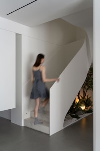 A woman wearing a dress walks up a modern minimalist staircase made of marble.