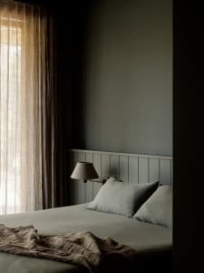 A minimalist bedroom with soft, neutral fabrics and textiles.