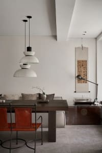 A modern interior design featuring a wooden dining table, leather chairs, and minimalist decor elements.