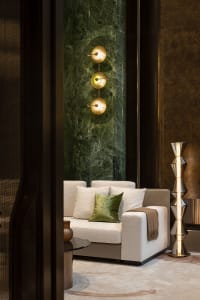 A modern living room featuring a white sofa with green and brown accents, illuminated by a unique light fixture, set against 