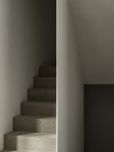 Dark staircase with wooden steps and concrete landings featuring a warm, ambient lighting setup.