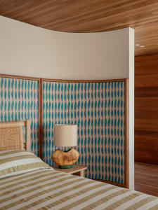 An industrial-style bedroom with a patterned wooden headboard and striped bedding.