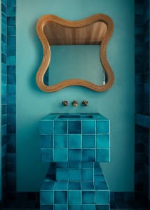 A modern bathroom with blue ceramic tiles and a concrete floor.