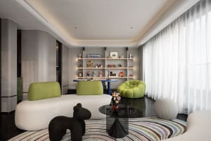 A modern living room with a white sofa, green armchairs, and a black coffee table.