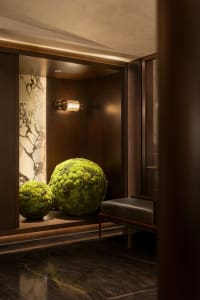 A modern lobby with marble walls and large, decorative moss spheres.