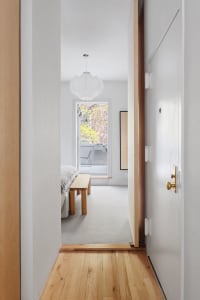 A minimalist bedroom with white walls and wooden furniture.