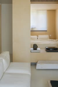 A minimalist bedroom featuring a wooden platform bed and white furniture.