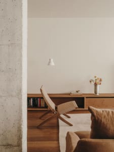Minimalist living room with wooden furniture and a concrete wall.