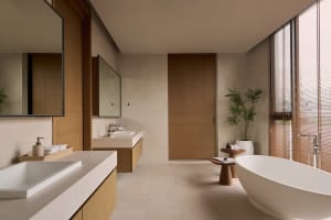 Modern bathroom with wooden doors, stone sink, and concrete floor and tub.