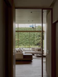 Modern cozy living room with a textured sofa and large windows overlooking a green outdoor area.