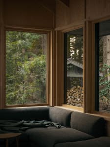 A modern interior design featuring wooden window frames and a cozy sofa with a blanket.