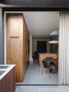 Modern kitchen featuring wooden cabinets and table with a hanging lamp.