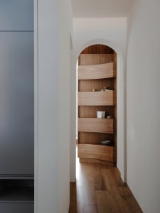 Modern minimalist wooden shelf with curved design and minimal objects.
