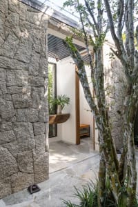 A modern, minimalist outdoor patio area with stone walls and a wooden bench.