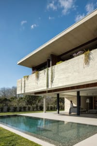 A modern house with a concrete exterior and green plants on the balcony.