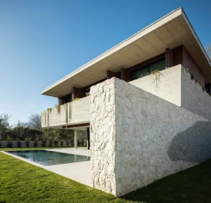 Modern residential house with a concrete exterior and a swimming pool in a green garden.