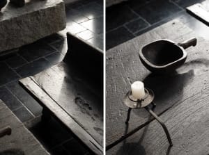 An antique wooden furniture piece with a candle and a wooden bowl on a vintage table.