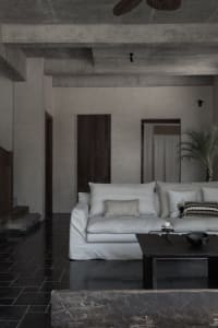 Contemporary living room with minimalist design, concrete flooring, and sleek white furniture.