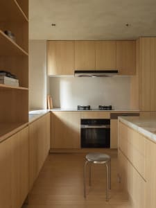 Modern kitchen with minimalist wooden cabinets, countertops, and flooring.