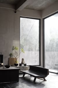 Minimalist living room with concrete elements and large windows.