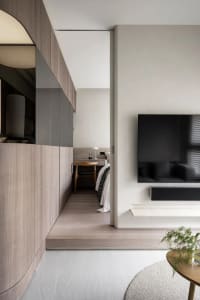 Modern minimalist living room featuring a flat-screen TV mounted on a wall, surrounded by sleek, contemporary furnishings and