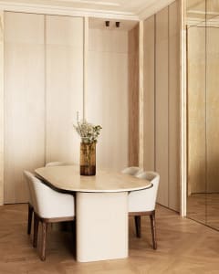 A modern dining room with a marble table and chairs, featuring a vase of flowers.