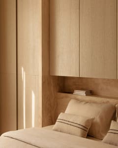 Minimalist bedroom with wooden paneled walls and beige bedding.