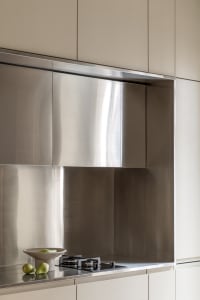 A minimalist kitchen with metal cabinets, a stainless steel backsplash, and a countertop.